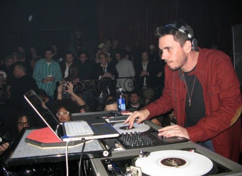 a dj with one headphone off while performing and cueing